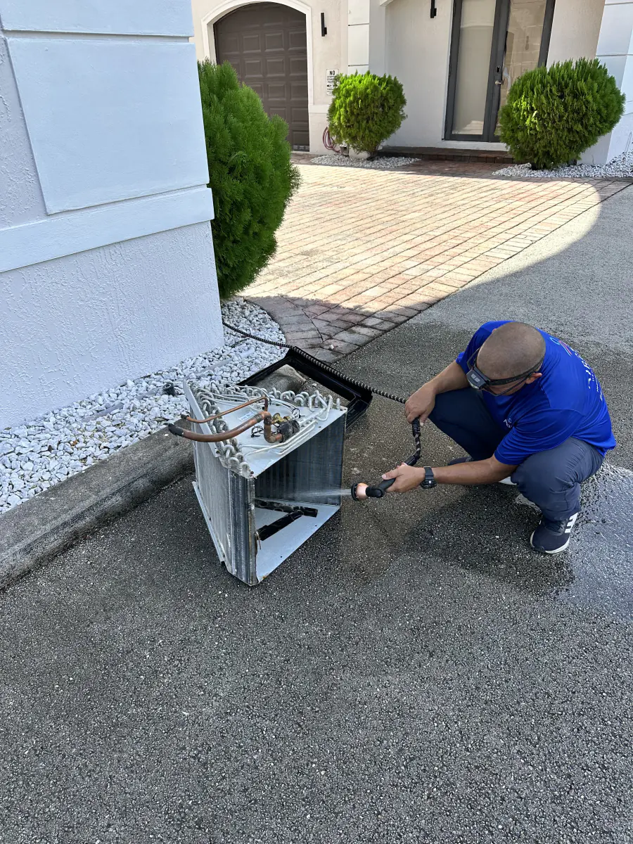 Técnico limpiando un serpentín de condensador en una casa del Sur de Florida
