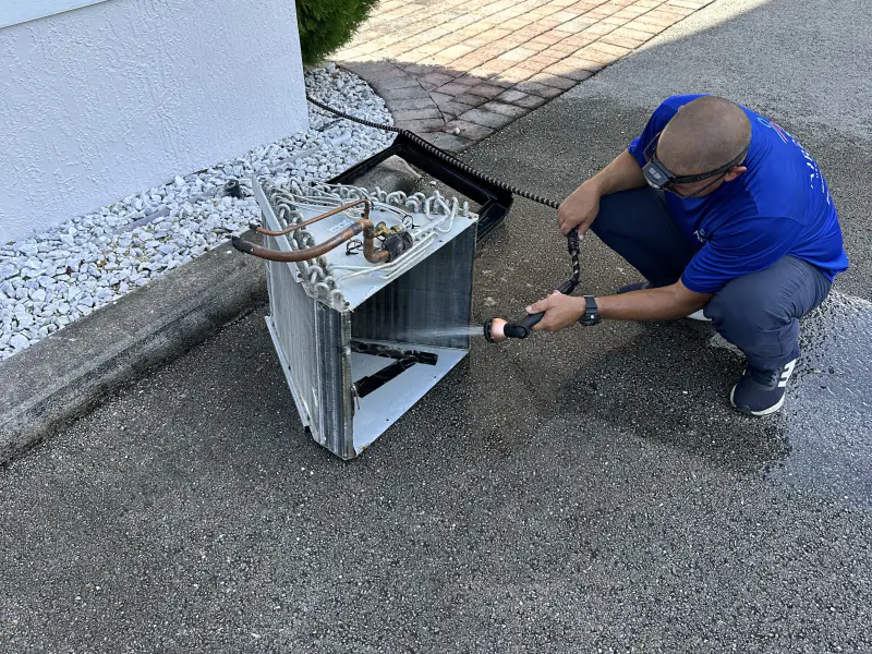 Technician cleaning an AC condenser coil