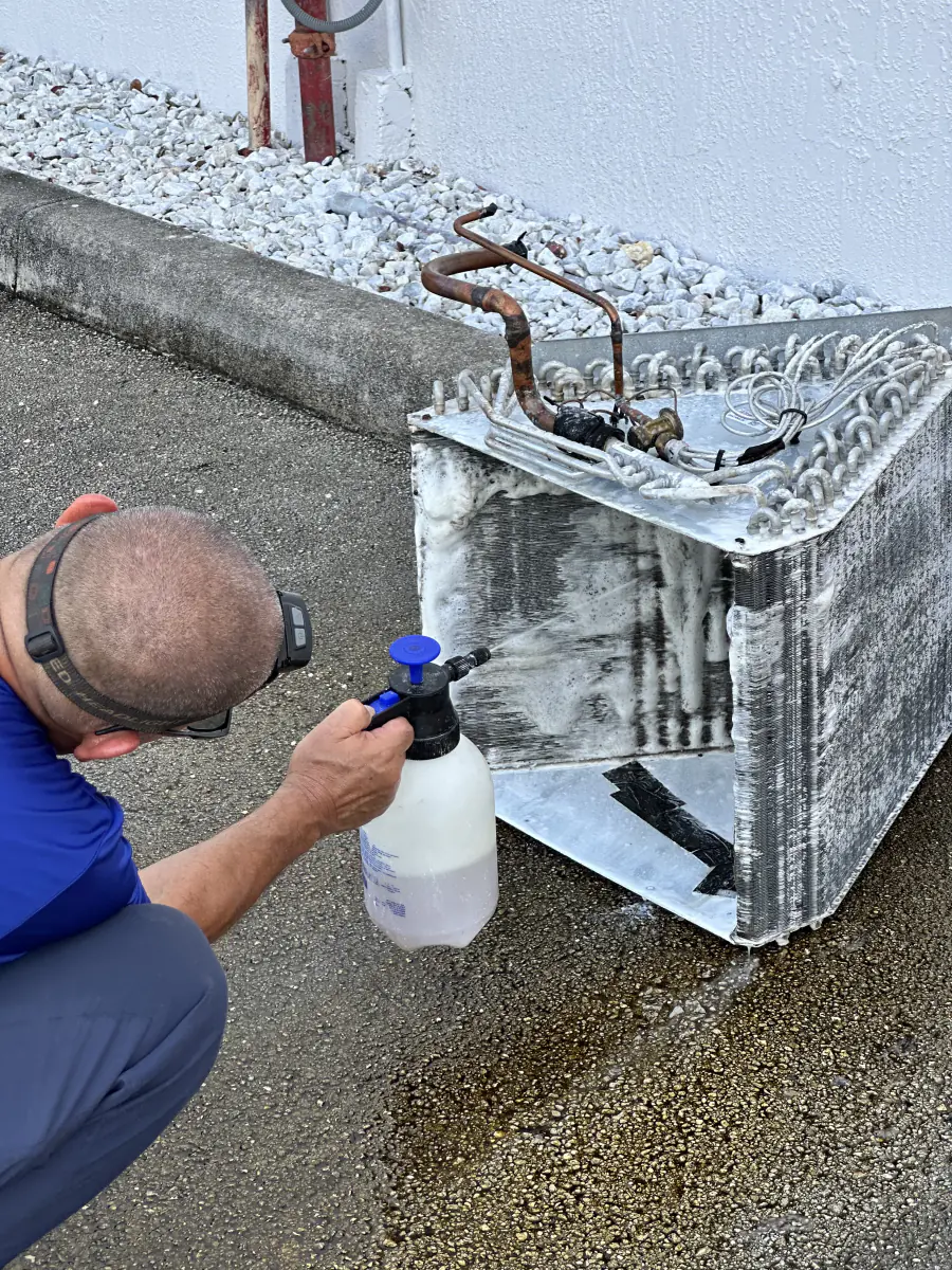Técnico aplicando limpiador al serpentín del condensador