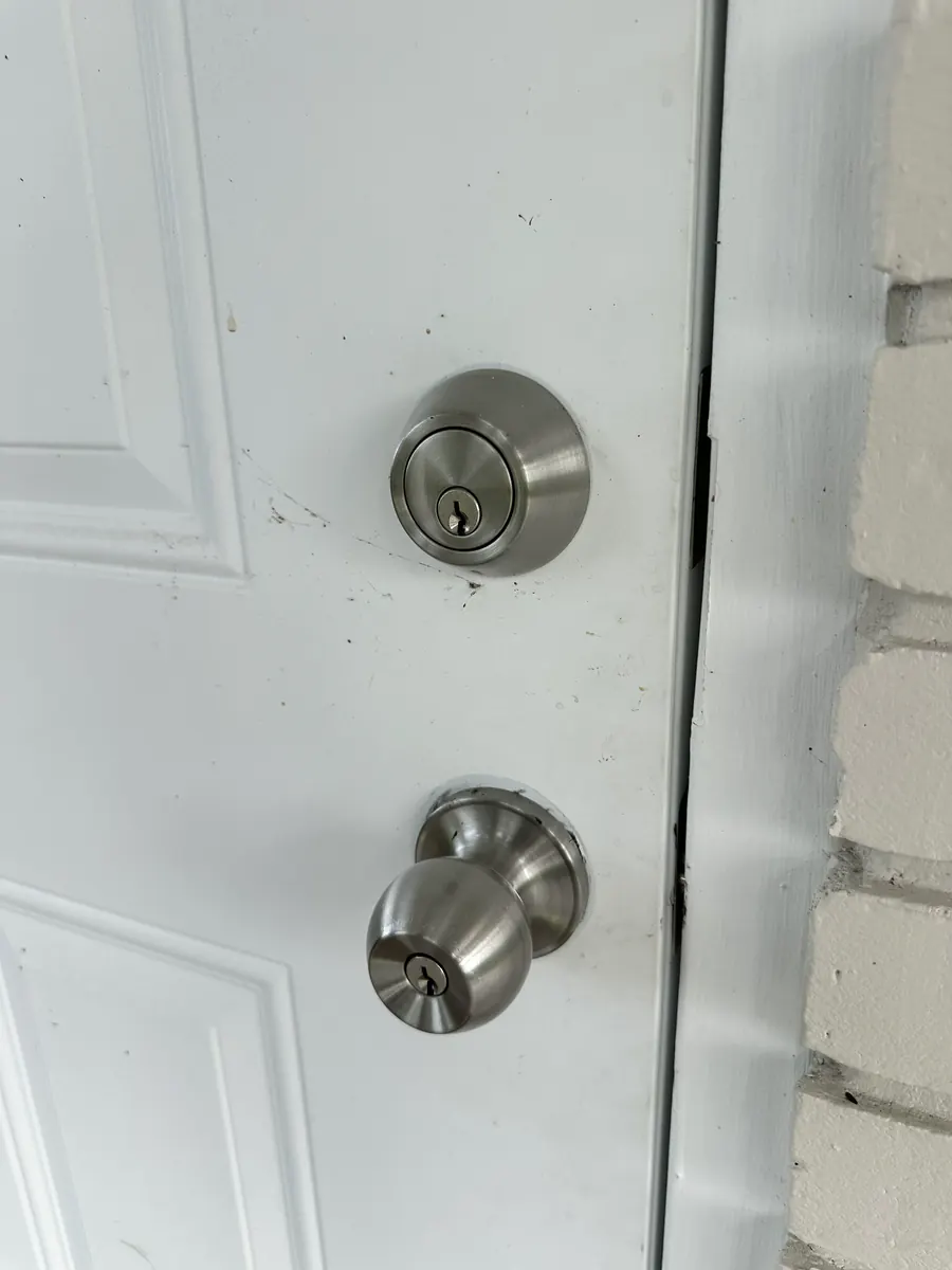 The same front door before, with a worn deadbolt and round knob