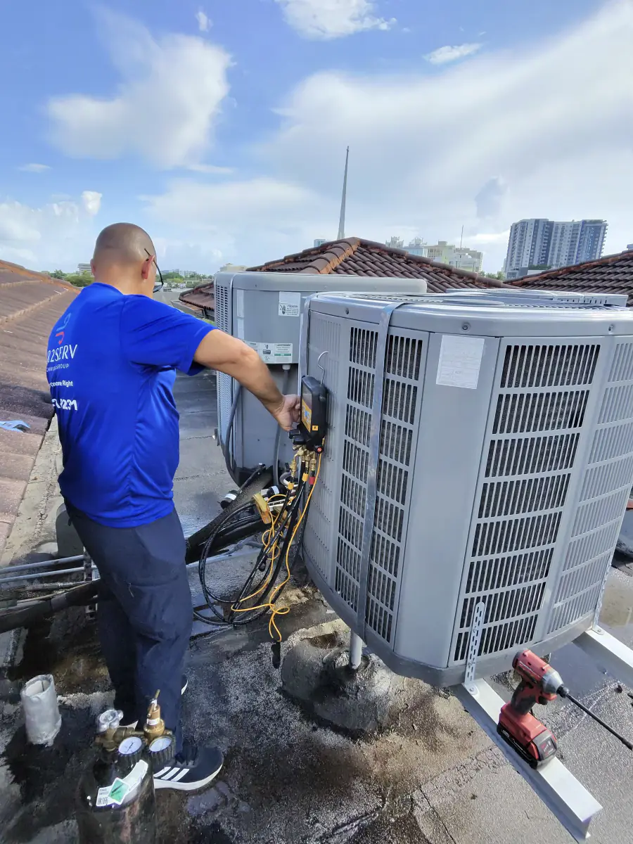 Técnico de Ibis Repair Group conectando manómetros a un condensador en un techo en Miami
